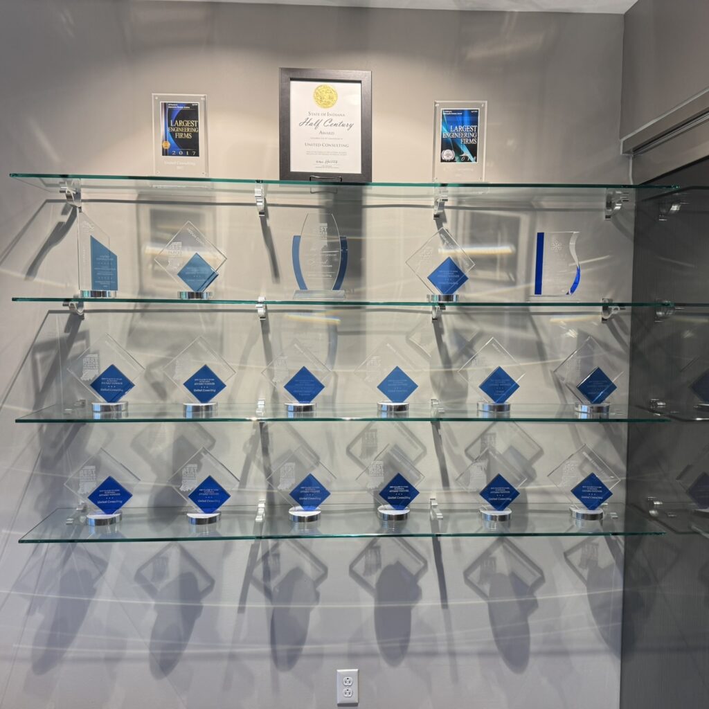 Glass-display case filled with blue diamond trophies and plaques, with a central framed certificate at the top shelf.